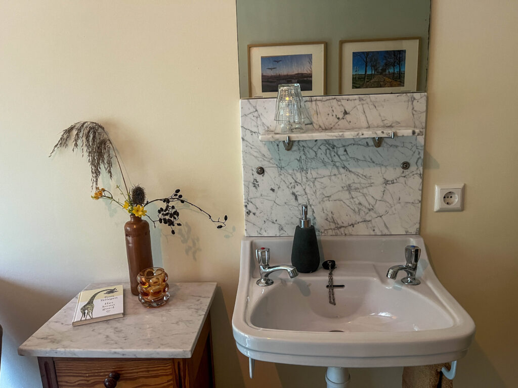 Kamer 1 met wastafel en gedeeld sanitair.